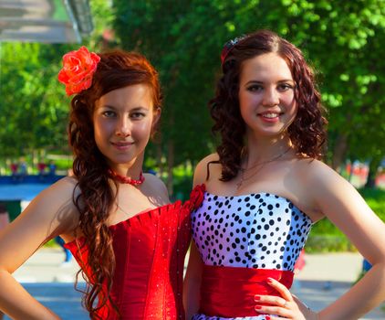 Two young girls in beautiful dresses in summer city park