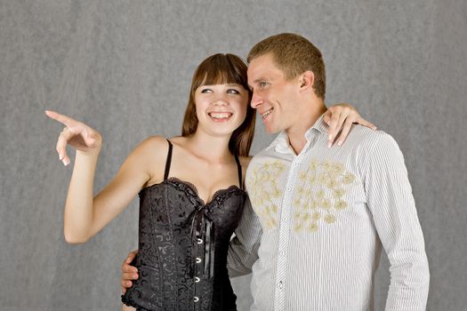 The guy and the girl happily smiling and looking in the direction that points to a girl