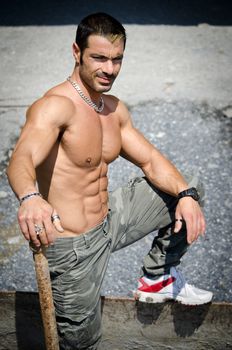 Sexy construction worker shirtless, showing muscular naked torso, abs and chest, outdoors