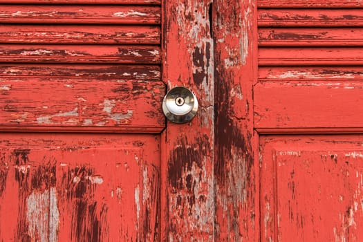 Old door red wood  peeling paint and knob