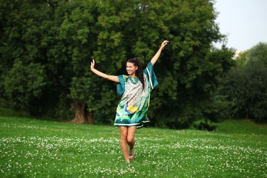 Beautiful young woman walking on the summer park