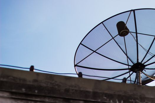 A satellite dish on a house blue sky background