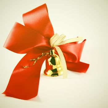 Red satin ribbon and golden bell with retro filter effect