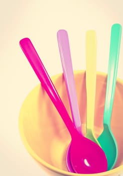 Group of plastic spoons in yellow bowl with retro filter effect