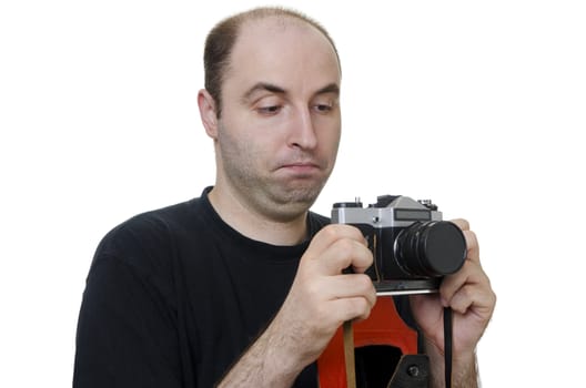 young man holding a vintage camera with lens cap on looking confused on white background