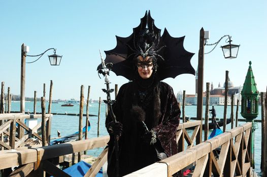 VENICE - MARCH 8: Lady dressed in costume of black bat near canal during the Carnival of Venice on March 8, 2011.The annual carnival was held in 2011 from February 26th to March 8th.