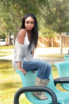 An extraordinarily beautiful young woman sits on a park bench.