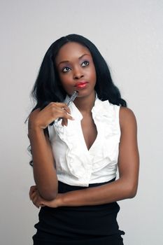 An extraordinarily beautiful, contemplative, young businesswoman holding an ink pen.