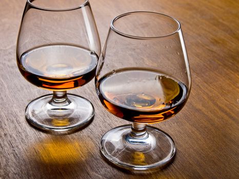 Two glasses of cognac on a wooden table