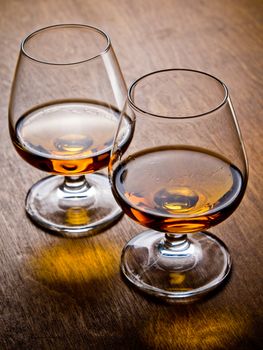 Two glasses of cognac on a wooden table