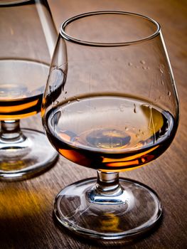 Two glasses of cognac on a wooden table