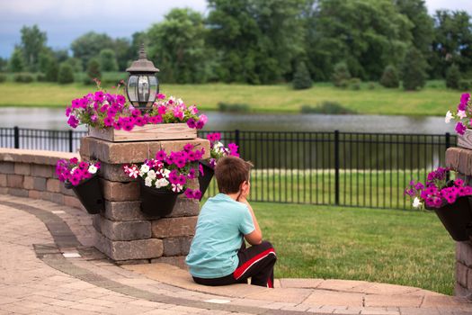 Eight years old boy enjoying his time by sitting on the steps and putting his hands on his chin