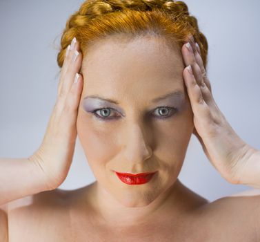 portrait of a red-haired blue-eyed woman keeps hands to temples
