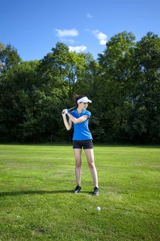 Pretty girl playing golf on grass in summer