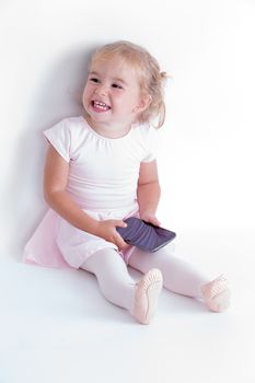 Young toddler holding a smart phone in her ballerina dress