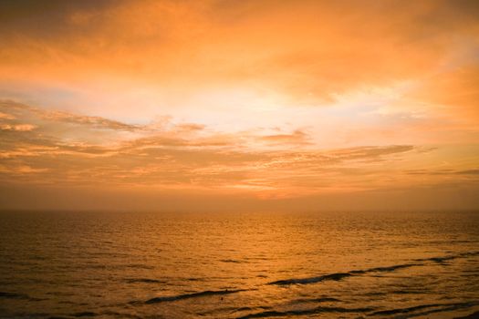 Tranquil yellow and orange sunset over seascape in india.