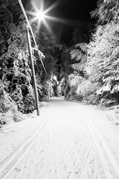 Black and white photo of a ski track at night