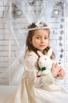 Girl in winter holiday dress with a toy rabbit