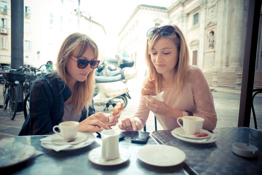 two beautiful blonde women talking at the bar in the city