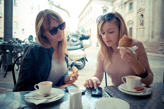 two beautiful blonde women talking at the bar in the city