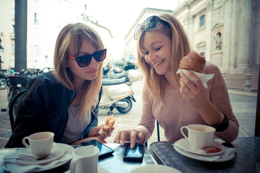 two beautiful blonde women talking at the bar in the city