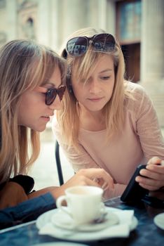 two beautiful blonde women talking at the bar in the city