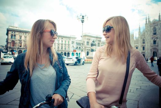two beautiful blonde women shopping on bike in the city
