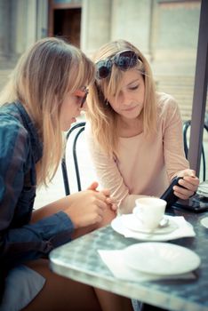 two beautiful blonde women talking at the bar in the city