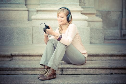 beautiful blonde woman listening to music in the city