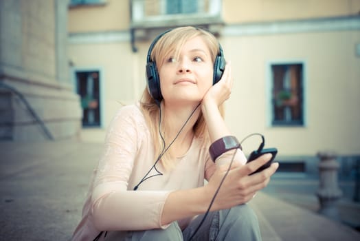 beautiful blonde woman listening to music in the city