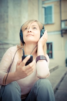 beautiful blonde woman listening to music in the city