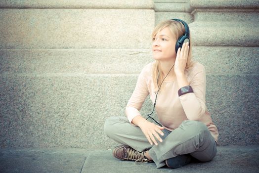 beautiful blonde woman listening to music in the city