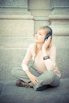 beautiful blonde woman listening to music in the city