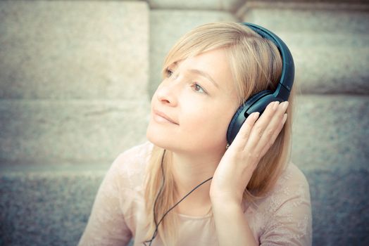 beautiful blonde woman listening to music in the city