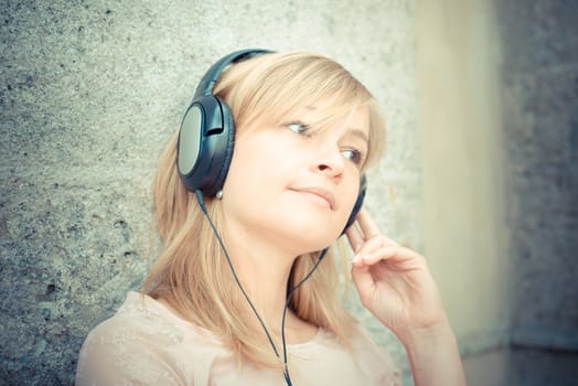 beautiful blonde woman listening to music in the city