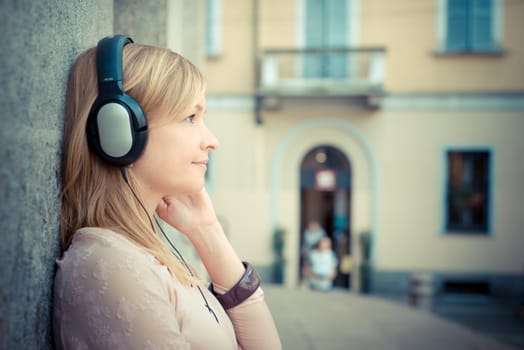 beautiful blonde woman listening to music in the city