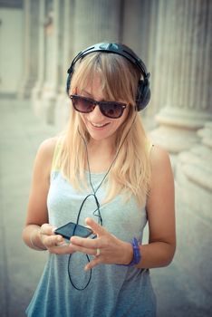 beautiful blonde woman listening to music in the city