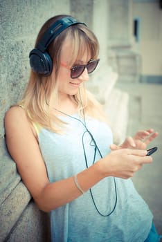 beautiful blonde woman listening to music in the city