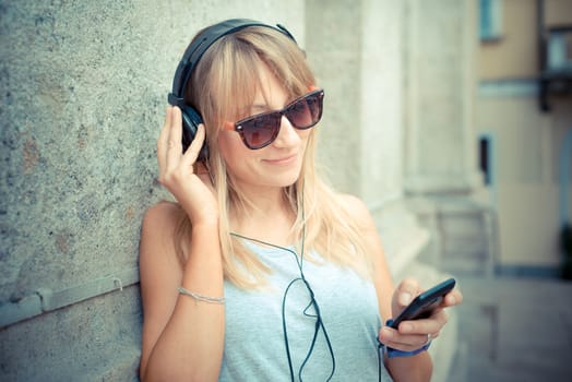 beautiful blonde woman listening to music in the city