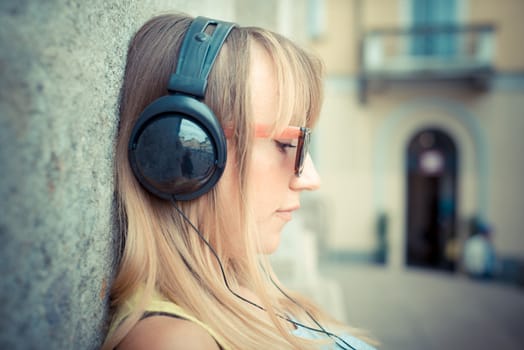 beautiful blonde woman listening to music in the city