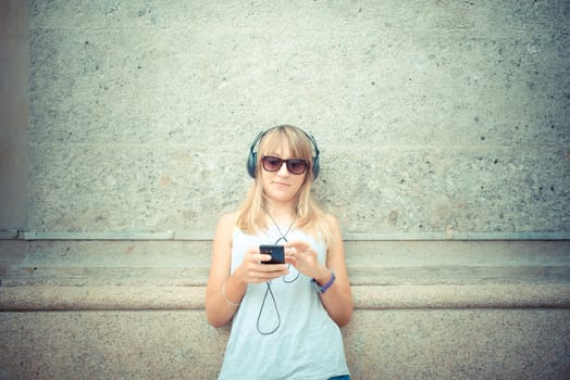 beautiful blonde woman listening to music in the city