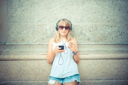 beautiful blonde woman listening to music in the city