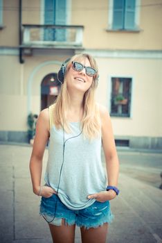 beautiful blonde woman listening to music in the city