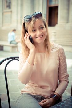 beautiful blonde woman on the phone at the bar in the city