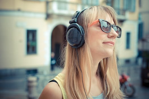 beautiful blonde woman listening to music in the city