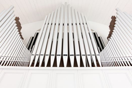 White church organ pipes photographed from below and in symmetry