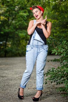 Beautiful pin-up girl in denim overalls and a T-shirt outdoors