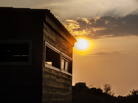 Sunset scene in the forest with a wooden house