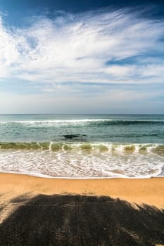 Beautiful blacksand beach in india. Waves hitting in to shore.