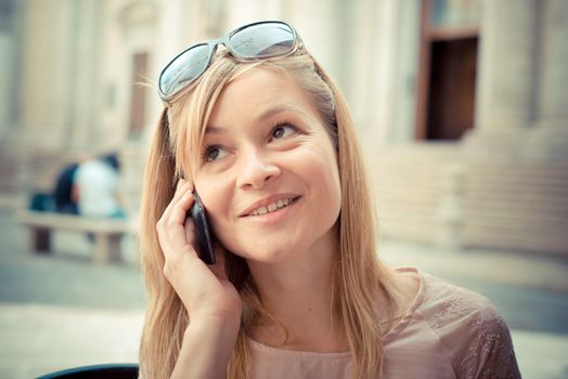 beautiful blonde woman on the phone at the bar in the city